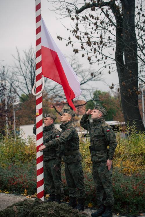 Wciągnięcie flagi Rzeczypospolitej na maszt - żołnierze salutują.